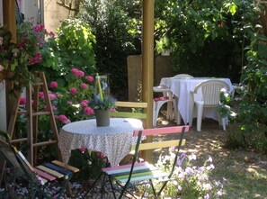 Een terras met een tuin, een ronde tafel, stoelen en een ladder.