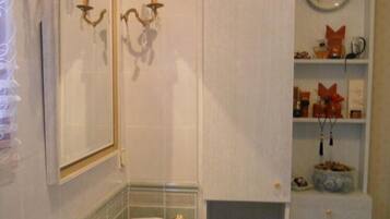Un baño con lavamanos blanco, dos apliques de pared, un espejo y un radiador.