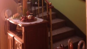 Una escalera con barandal de madera y un jarrón con flores en el rellano.