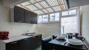 A compact kitchen with a coffee machine, a sink, and a dining area with a table set for two. - Valletta Kampnar City Living (Valletta)