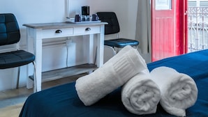 A hotel room with a bed, a desk, two chairs, a TV, and a red door. - Valletta Kampnar City Living (Valletta)