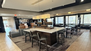 En modern hotellobby med en central bardisk, sittgrupper och stora fönster med fin utsikt.