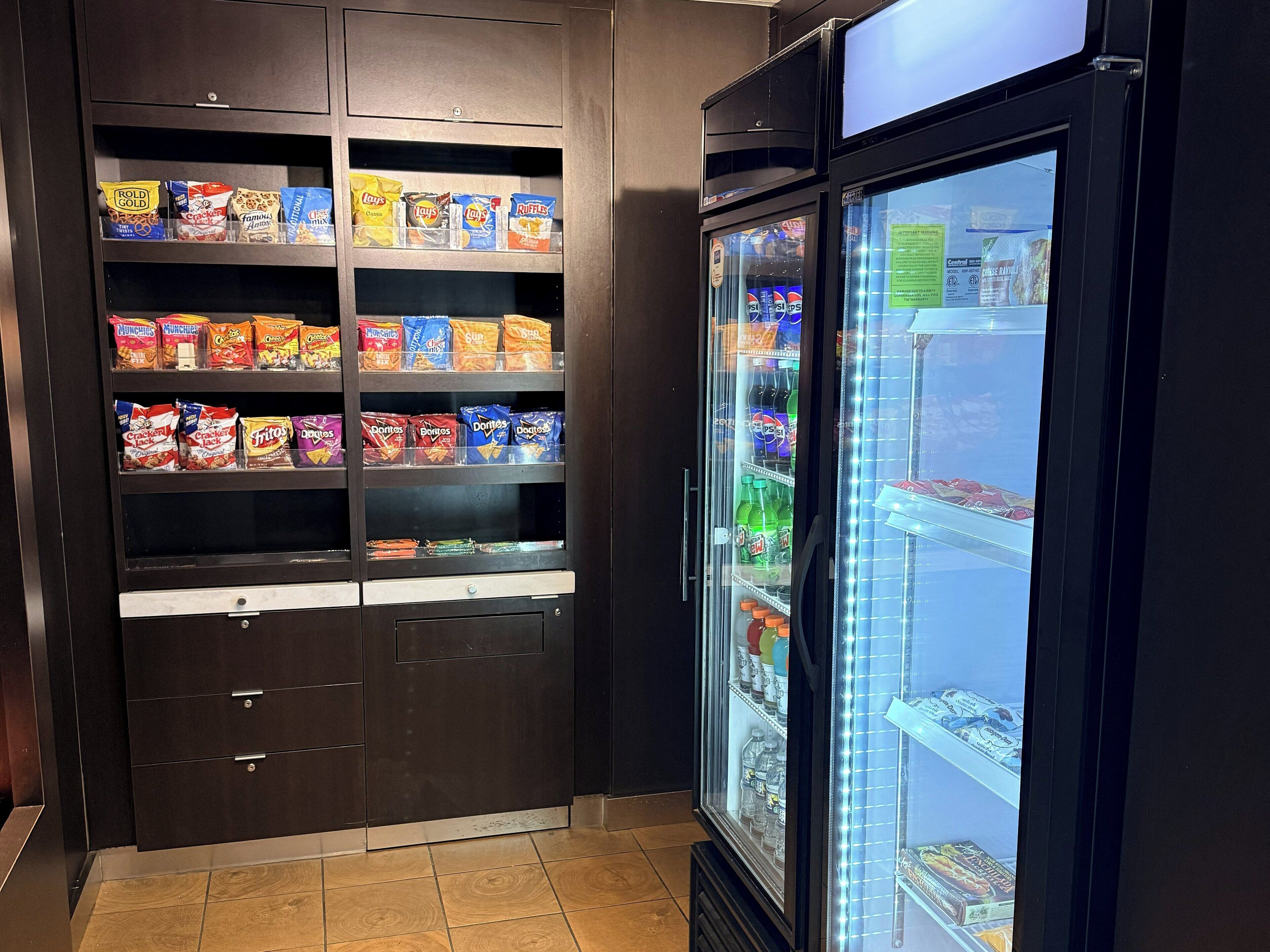 En snackautomat fyldt med chips og et kølet køleskab.