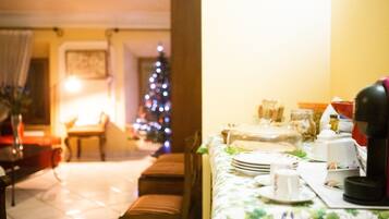 Uma sala de jantar com uma árvore de Natal, uma mesa posta com pratos, copos e uma cafeteira.