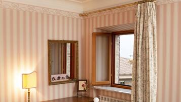 Un dormitorio con cama, cómoda, espejo y ventana con cortinas.