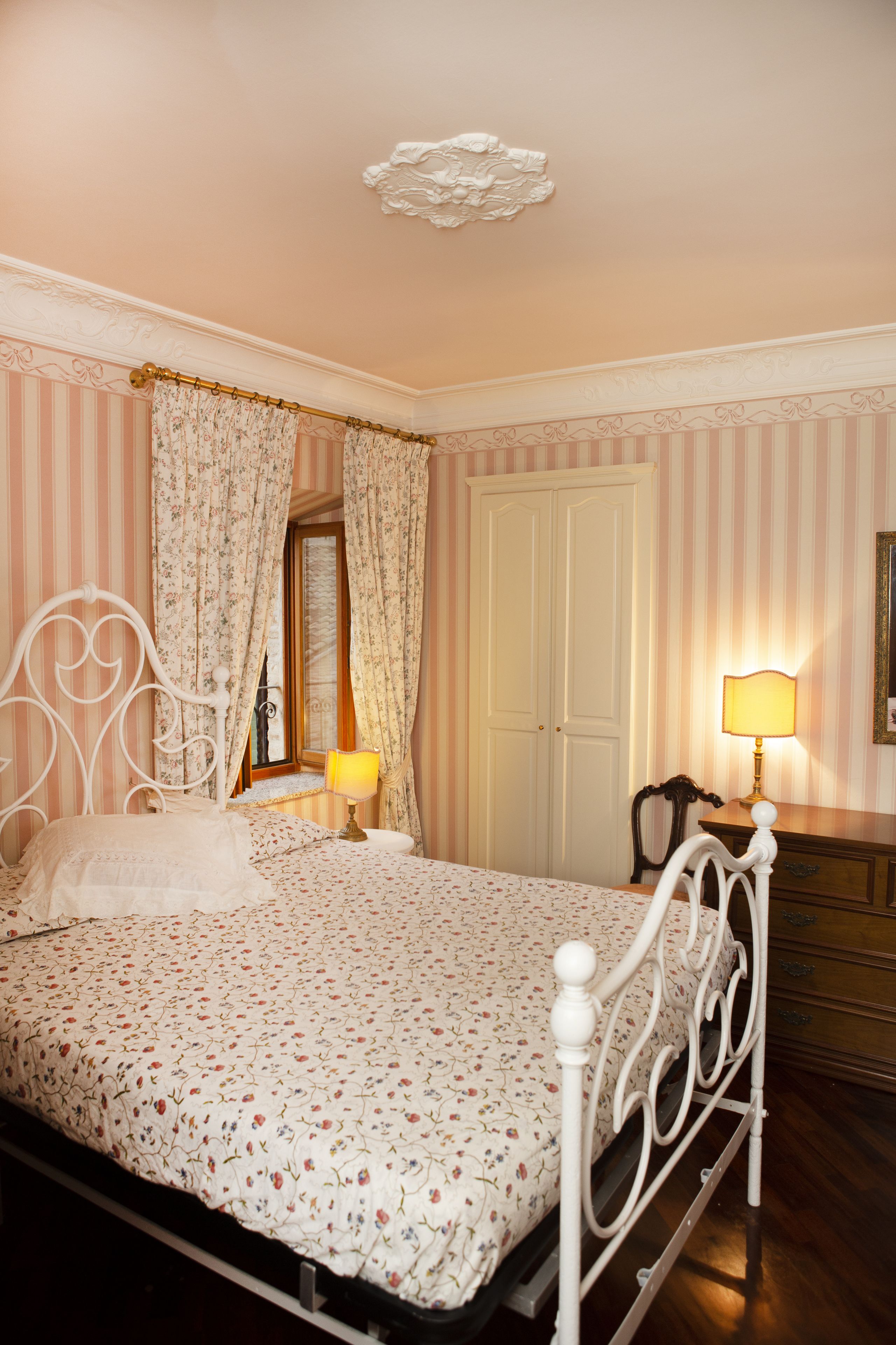 A bedroom with a bed, a nightstand, a lamp, and a wardrobe.