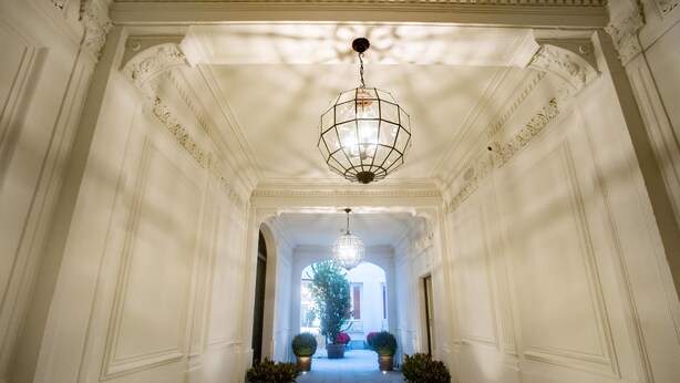 A grand hallway with ornate white walls, a central chandelier, and potted plants. - Soho Boutique Congreso (Madrid)
