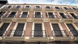 A multi-story building with a symmetrical facade, featuring evenly spaced windows and balconies with ornate metal railings. - Soho Boutique Congreso (Madrid)