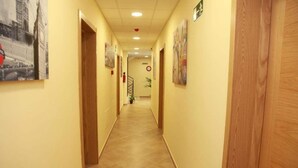 A hallway with wooden doors, tiled flooring, and wall-mounted artwork. - Hostal Doña Manuela (Málaga)