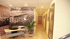 A reception area with a desk, chair, and a large poster of a cityscape. - Hostal Doña Manuela (Málaga)