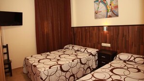A hotel room with two beds, a TV, a wooden headboard, and a painting on the wall. - Hostal Doña Manuela (Málaga)