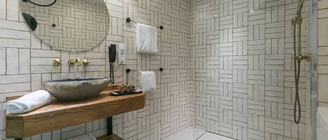 Un baño moderno con tocador de madera, un espejo grande y zona de ducha.