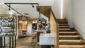 A modern interior with a wooden staircase, a wine display, and a bar area. - Hotel Pousada Real (Caldas de Reis)