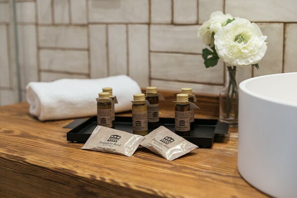A wooden table with toiletries, a white towel, and a vase with white flowers.