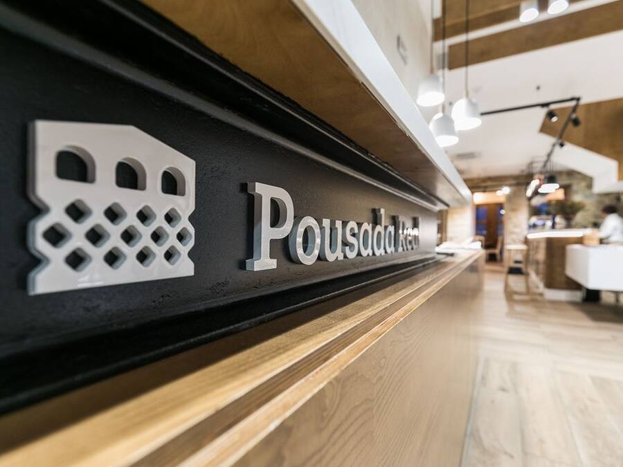A reception desk with a sign reading "Pousada do Rio" and a decorative metal piece above it.
