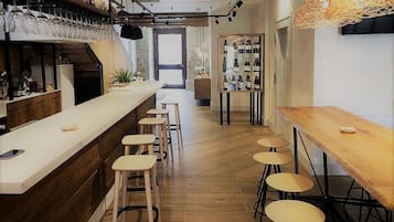 A bar area with stools, a counter, and shelves with bottles.