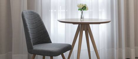 A modern room with a round wooden table and a grey upholstered chair.