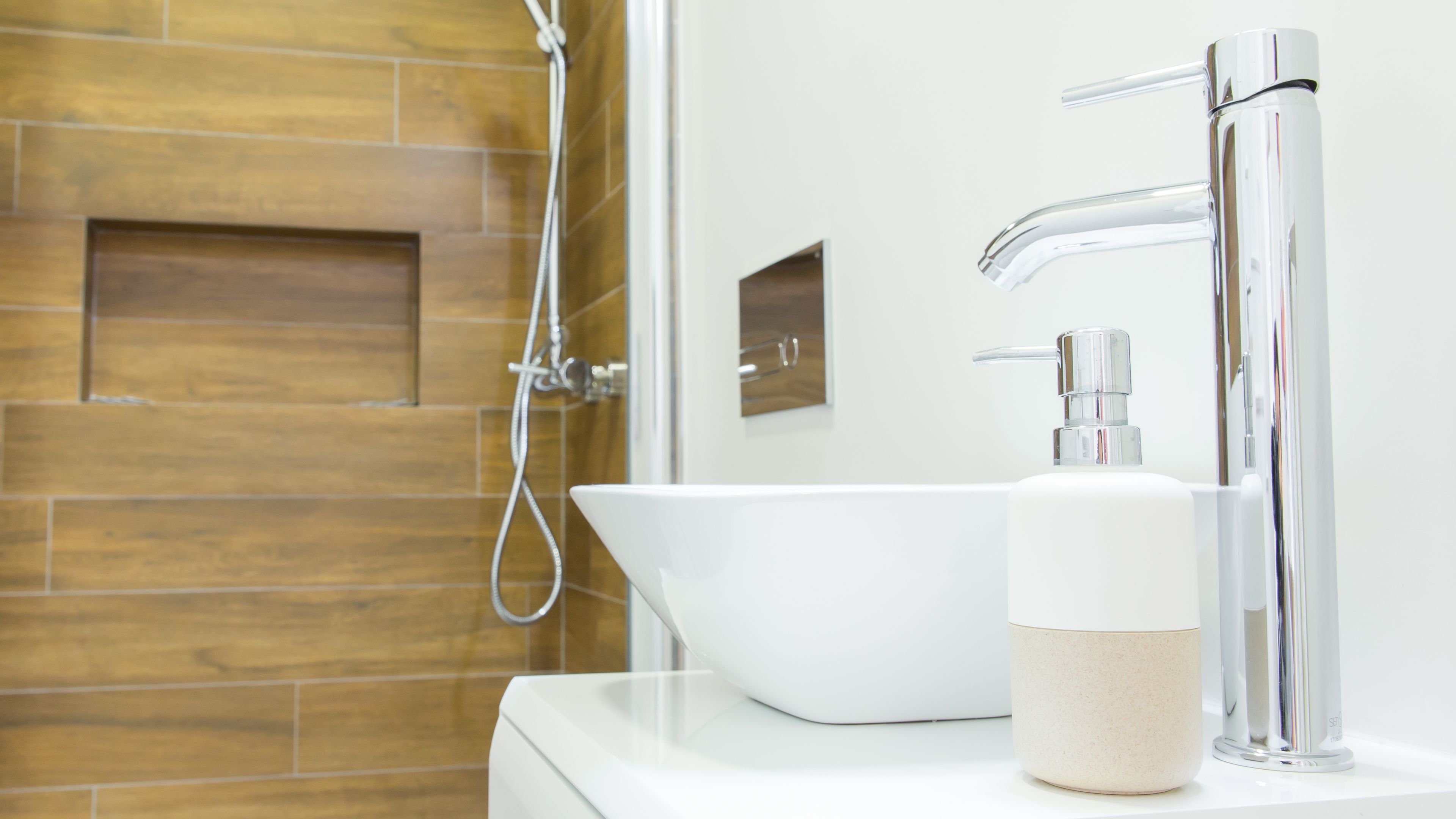 Een moderne badkamer met een wit wastafel, een chromen kraan en een handdouche.