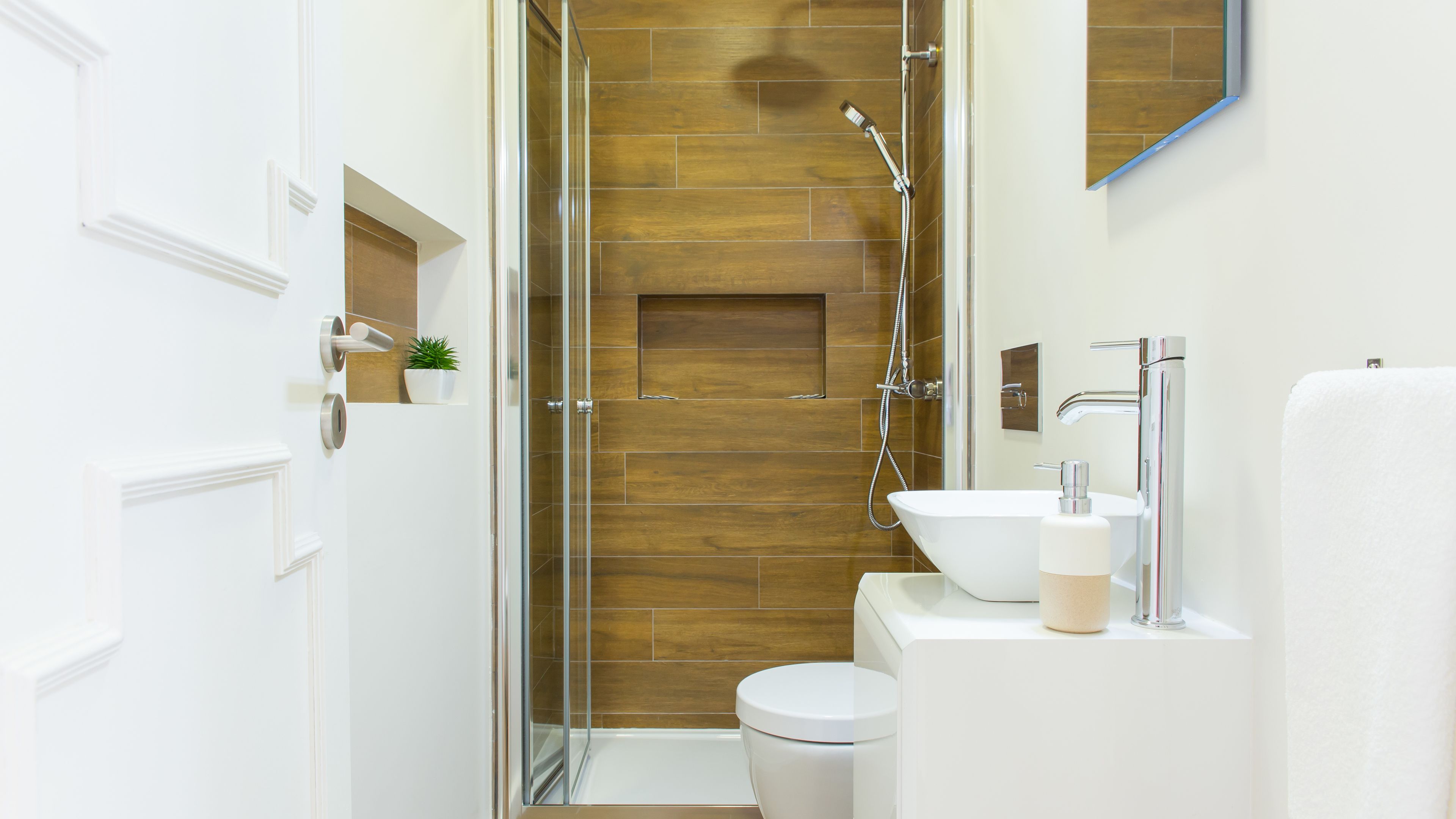 Un bagno moderno con doccia vetro, un WC bianco e un lavabo con specchio sopra.
