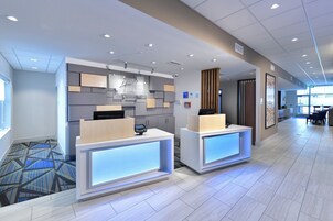 Zona de recepción de un hotel con dos mostradores, un diseño moderno con paneles de pared geométricos y un mostrador de registro.