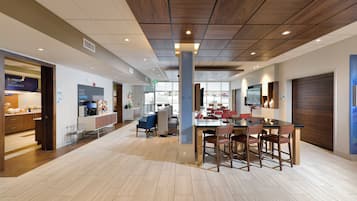 Un interior de cafetería moderno con techo de madera, una mesa central para comer con sillas y una máquina de espresso a la vista.