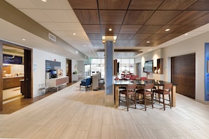 Un interior de cafetería moderno con techo de madera, una mesa central para comer con sillas y una máquina de espresso a la vista.