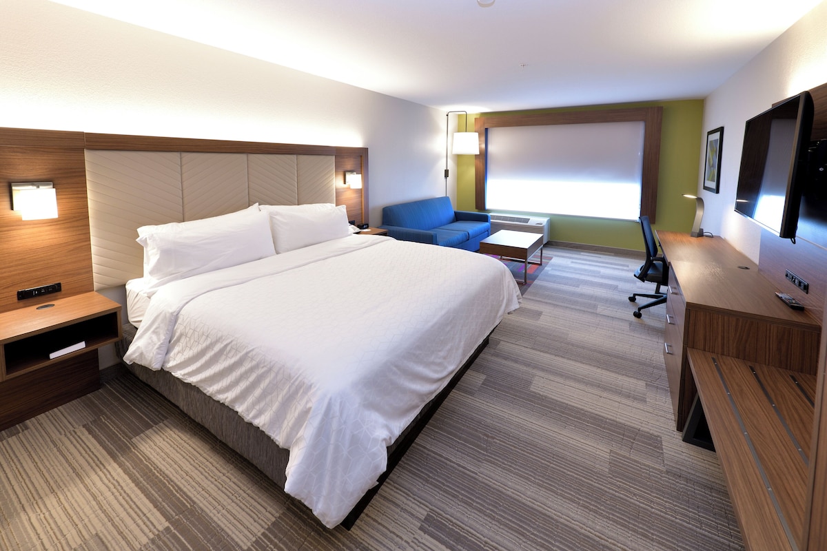 Une chambre d’hôtel avec un grand lit, un bureau, une chaise et un téléviseur.