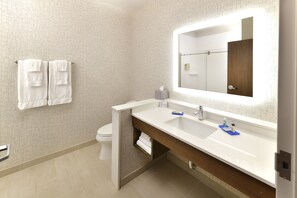 Une salle de bain moderne avec un lavabo blanc, un miroir et deux serviettes blanches accrochées au mur.
