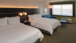 A hotel room with two beds, a nightstand, a desk, and a large window.