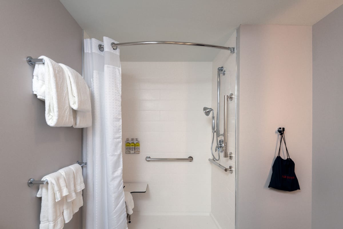 A modern bathroom with a walk-in shower, towel racks, and a grab bar.