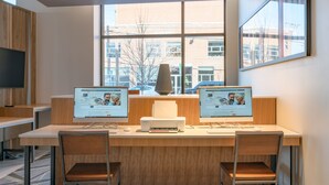 A modern office space with two desks, each with a computer and a printer, and two chairs.