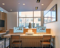 Un espacio de oficina moderno con dos escritorios, cada uno con una computadora e impresora, y dos sillas.