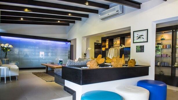 Een modern interieur met een centraal zwart aanrecht, blauw-witte poufs en een muur met tekst over gezondheid.