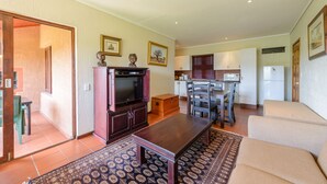 Een woonkamer met een televisie, bank en een eethoek.