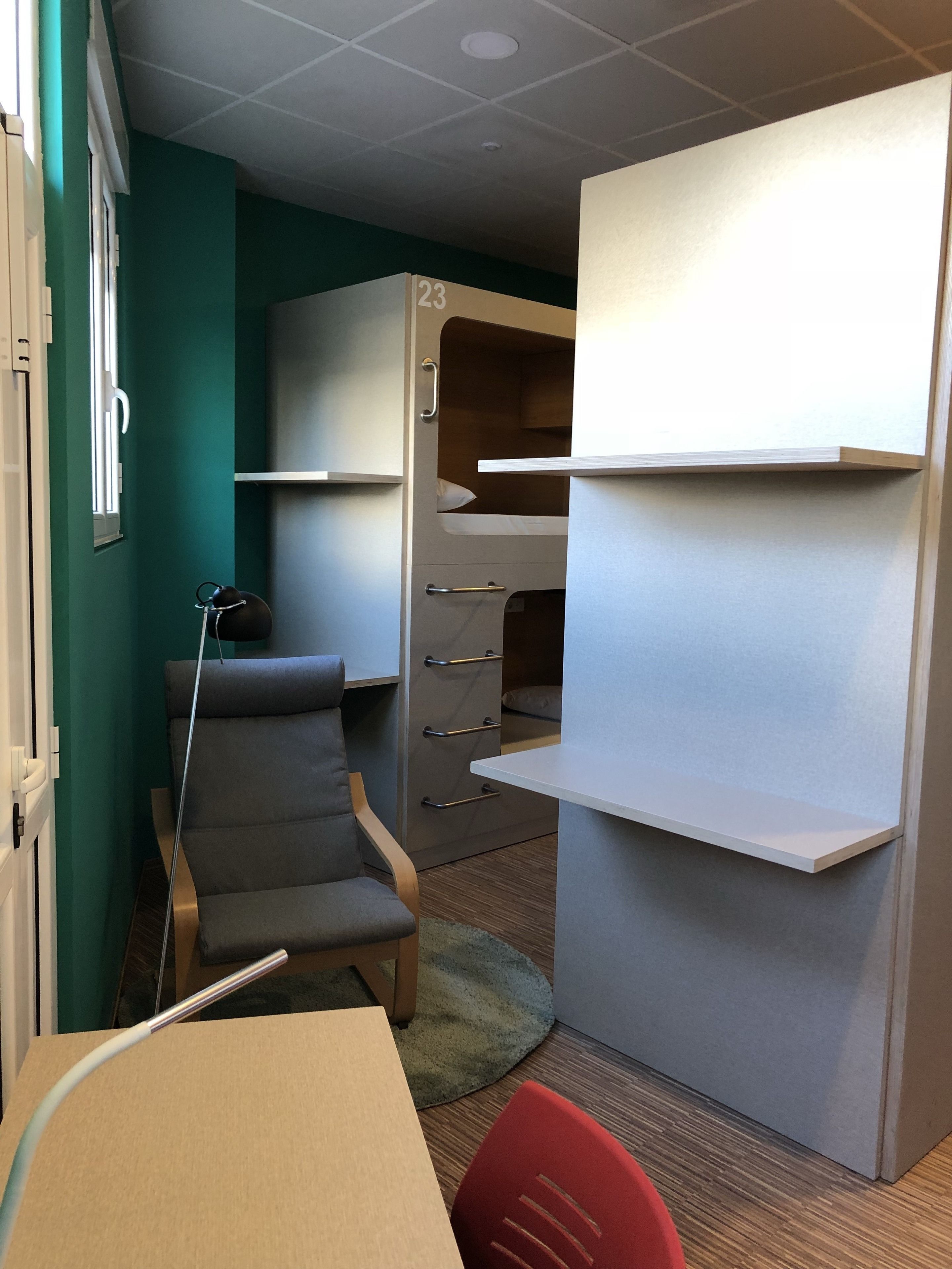 A compact room with a bunk bed, a desk, a chair, and a small table.