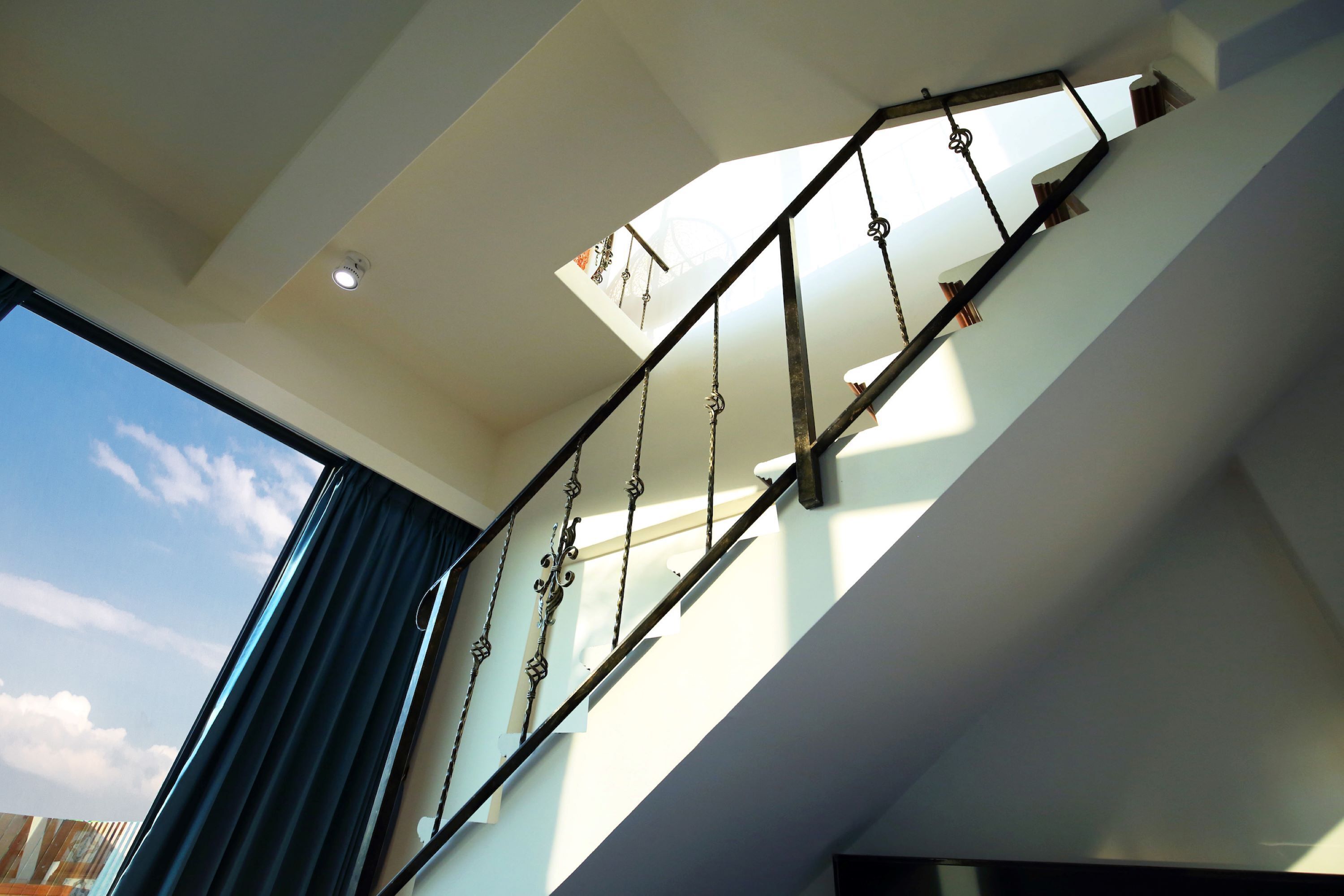 A modern staircase with metal railings and a skylight.