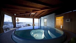 Un jacuzzi con vistas al mar, vigas de madera en el techo y un diseño de interiores moderno.
