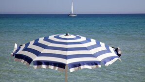 Una sombrilla de playa con un estampado azul y blanco a rayas.
