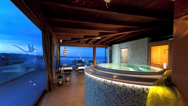 Un espace spa comprenant un bain à remous, une vue sur la mer et un balcon avec des sièges.