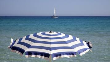 Un parasol de plage avec un voilier en arrière-plan.