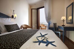 Habitación de hotel con una cama, un escritorio, una silla y vistas al mar.
