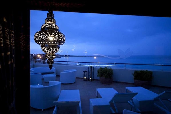 Terraza en la azotea con mobiliario y una lámpara colgante decorativa.