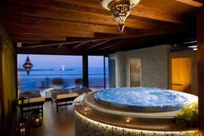 A hot tub in a room with a view of the sea, wooden ceiling, and a door. - Miraspiaggia (San Vito Lo Capo)