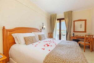 Una habitación de hotel con una cama de madera, un escritorio y vista al mar.