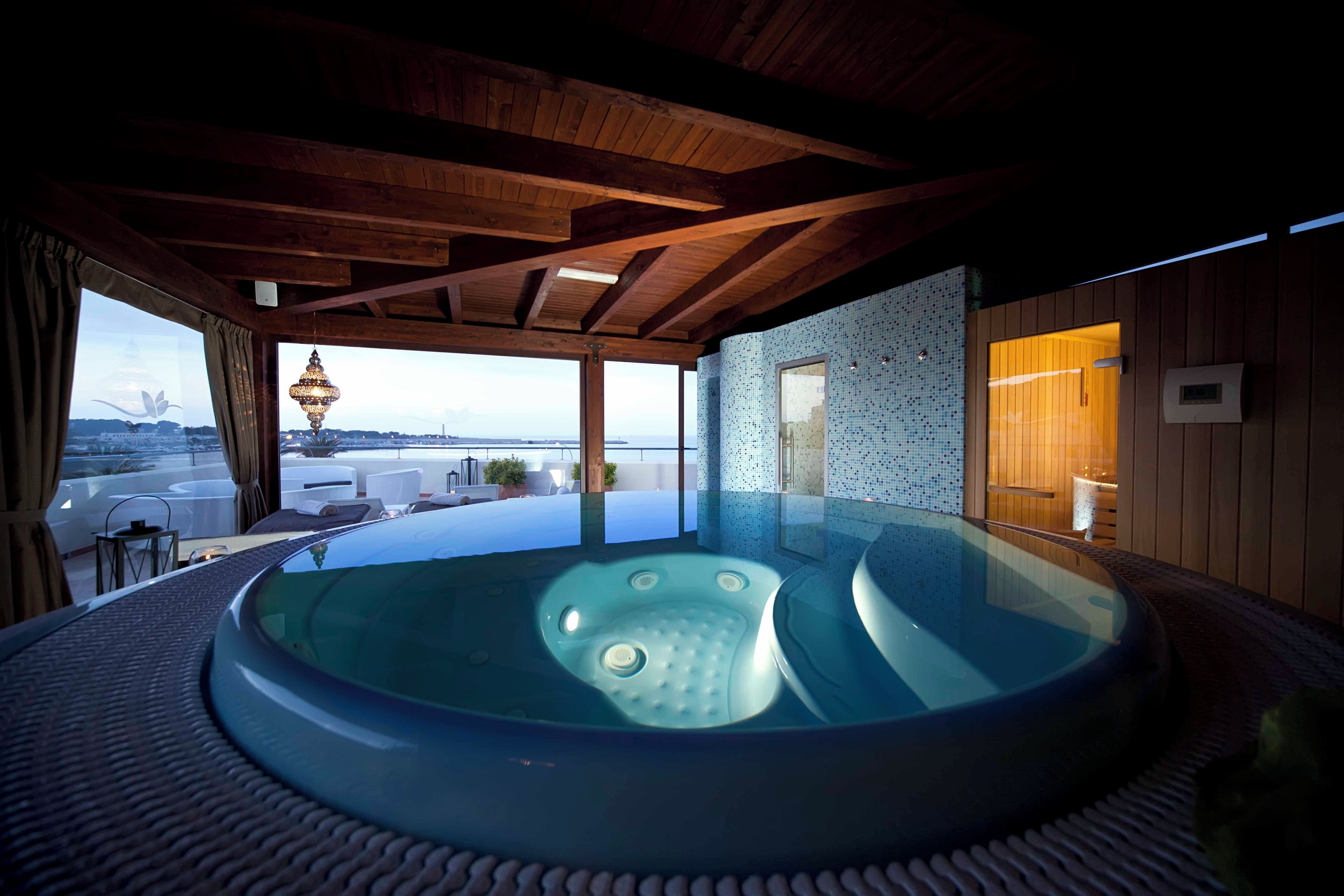 Ein Whirlpool mit Meerblick, Holzbalkendecke und einer gefliesten Wand.