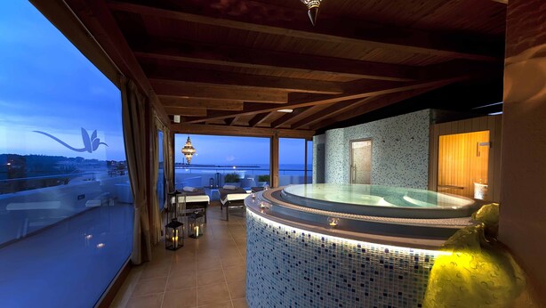 Un área de spa con hidromasaje, vistas al mar y techo de madera.