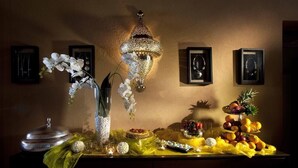 Una mesa con un centro de mesa decorativo, una lámpara de pared, cuadros enmarcados y una exposición de frutas.