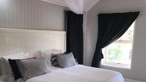 A bedroom with a bed, white bedding, a nightstand, a window with curtains, and a ceiling fan. - Visgraat Luxury Self Catering Unit (uMhlabuyalingana)