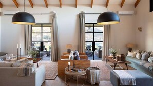 A spacious living room with large windows, a high ceiling with exposed beams, and a cozy seating area with sofas and a coffee table. - Simbavati Cederberg Ridge (Cederberg)
