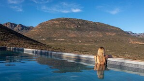 A person standing in a clear pool with a mountainous landscape in the background. - Simbavati Cederberg Ridge (Cederberg)